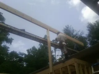 Carpenter setting a ridge beam over a new addition frame — Ice Dam Removal by Roofing Brothers in Waterford