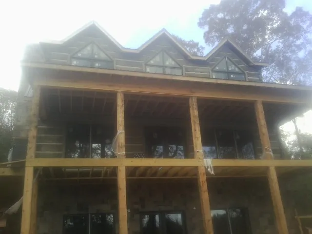 Dormers and porch framing on a large log home under construction — Roof Coating work by our crew in Waterford