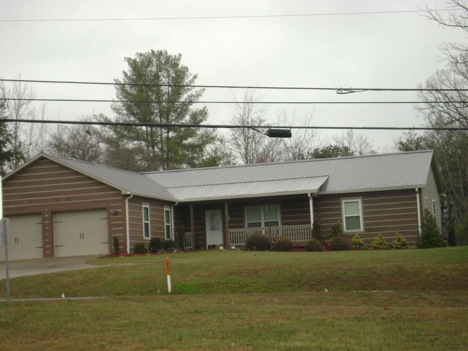 Gray metal roof on a log sided ranch home with a front porch in Waterford